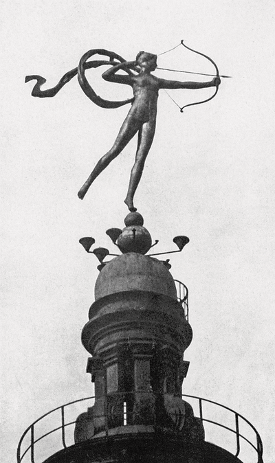 A black-and-white image depicting a weathervane atop a building's cupola of a nude woman, the Roman goddess of the hunt, Diana, aiming a drawn bow in front of her with a ribbon of fabric billowing out behind her shoulders.